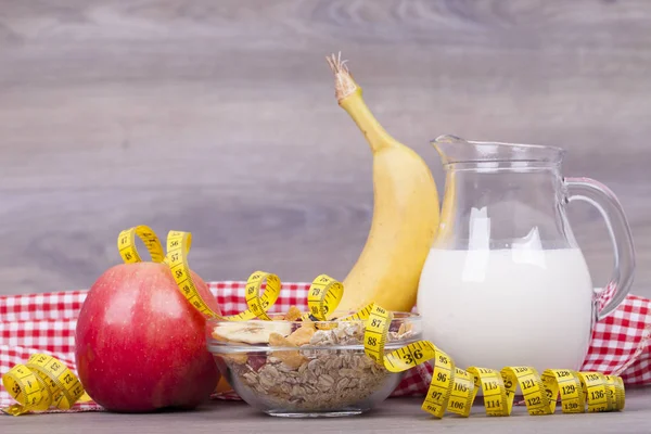Fitness concept with yoghurt, muesli and fruit on a wooden background