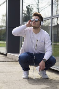Yakışıklı genç müzik açık havada için dinleme sahiptir. Seçici odak ve küçük alan derinliği.