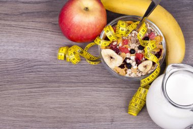 Diyet kavramı ile müsli, yoğurt, muz ve elma ahşap arka plan üzerinde. Metniniz için boş alan ile.