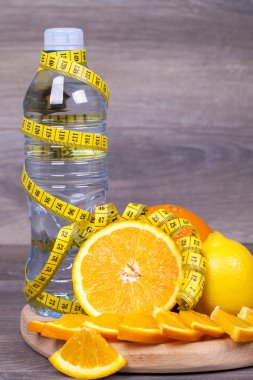 Bir şişe su, limon ve portakal ahşap arka plan üzerinde diyet kavramı