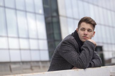 Köprüde duran, çit yaslanmış ve bekleyen düşünceli bir genç adam portresi