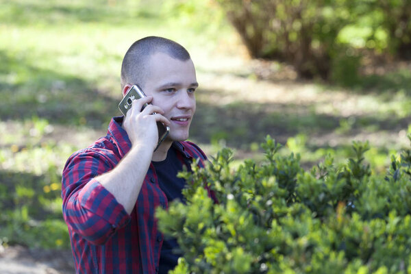 Handsome young man phoning and enjoys the outdoors. Selective focus and small depth of field.