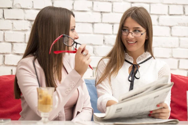 Две Молодые Девушки Деловой Встрече Листают Газету Разговаривают — стоковое фото