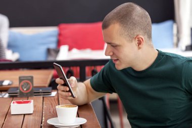 bir fincan kahve ve bir telefon Mobile içme bir kafede genç adam