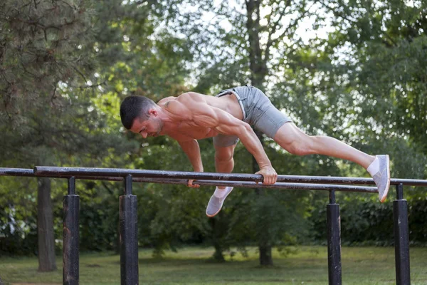 Genç Kas Genç Adam Parkta Paralel Çubuklarındaki Egzersizleri Yapıyor — Stok fotoğraf