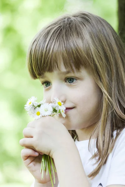 公园里的小女孩闻到野花的味道 有选择的焦点和小的景深 镜头耀斑 — 图库照片