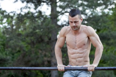 Egzersiz ve fitness kavramı. Yakışıklı genç kaslı adam yatay çubuğu egzersizleri yapıyor