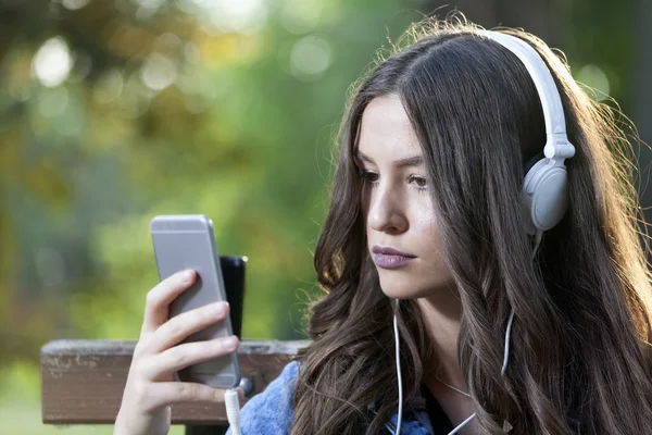 Piękna Młoda Kobieta Siedzi Ławce Parku Słuchanie Muzyki Posiadania Telefonu — Zdjęcie stockowe