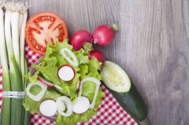 Ahşap bir masa üzerinde çok lezzetli taze salata. Marul, turp, soğan, domates ve salatalık. Metniniz için boş alan ile. Yukarıdan görüntülemek.