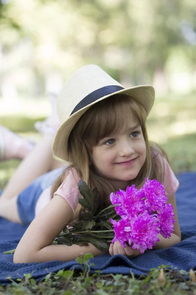 Vacker Flicka Med Hatt Liggande Gräset Och Hålla Bukett Blommor — Stockfoto