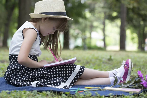 Menina Bonito Com Chapéu Vestido Senta Natureza Grama Escreve Desenha — Fotografia de Stock