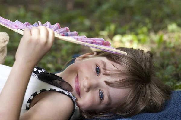 可爱的小微笑的女孩与蓝眼睛躺在草地上 — 图库照片
