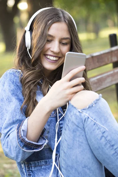Piękna Młoda Uśmiechający Się Kobieta Siedzi Ławce Parku Słuchanie Muzyki — Zdjęcie stockowe
