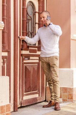 Yakışıklı genç işadamı kapı ve görüşmeler bir cep telefonu üzerinde açma. Çalışmaya geliyor