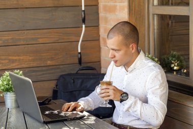 Modern kahve dükkanı Ardiles, Genç ahşap bir masa otururken dizüstü bilgisayar üzerinde çalışan yakışıklı genç işadamı dostum içme kahve Cafe ve dizüstü bilgisayar kullanarak