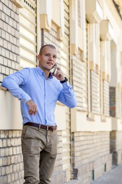 Genç işadamı eski bir binanın önünde duruyor ve bir cep telefonu üzerinde görüşmeler. 