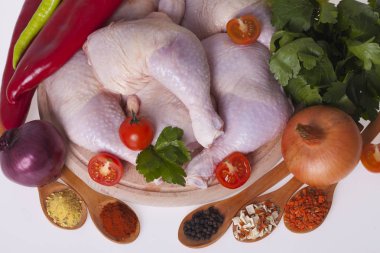 Taze tavuk uyluk ve sebze ile ahşap bir gemide sopaları ve baharat beyaz bir arka plan üzerinde.