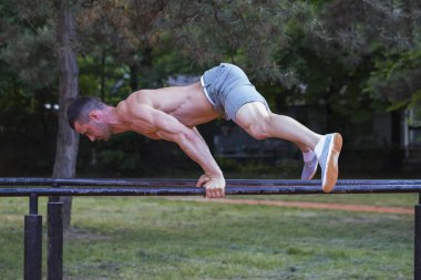 Parkta paralel çubuklarındaki egzersizleri yapıyor Kas Genç delikanlı. spor, fitness, egzersiz ve insanlar kavramı