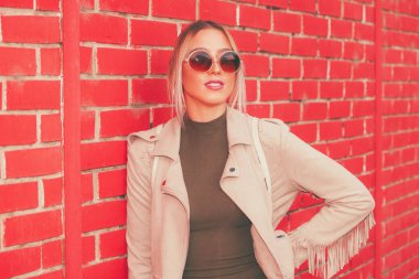 Duran kırmızı tuğla duvar arka plan, güneş gözlüklü bir güzel genç modern ve kentsel kadın portresi kapatın.
