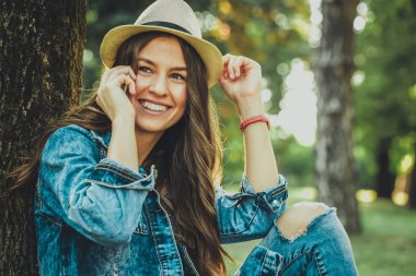 Güzel kız cep telefonu üzerinde konuşurken. Smartphone bir parkta dışında mutlu gülümseyerek kullanan rahat güzel kız. Açık şapka ile modern trendy kız portresi