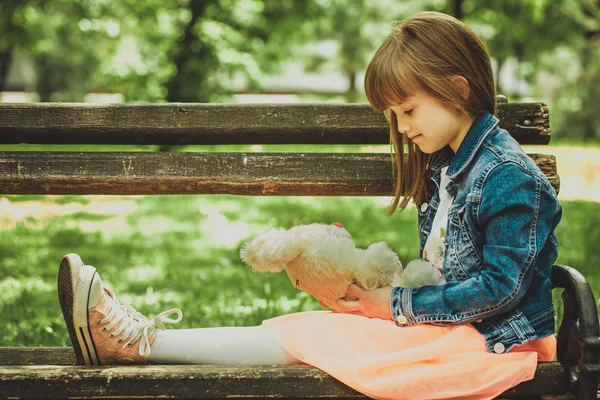 Menina Feliz Sentada Banco Parque Segurando Nas Mãos Seu Brinquedo — Fotografia de Stock