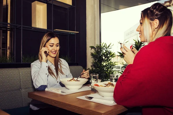 Друзья Женщины Обедают Вместе Ресторане Две Молодые Женщины Пользующиеся Мобильным — стоковое фото