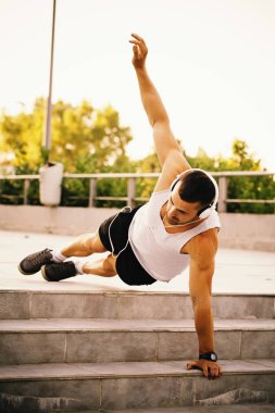 Eğitim parkta hazırlanıyor genç sporcu germe egzersiz yapmak. Egzersiz yaparken, o kulaklık aracılığıyla müzik dinler. Fitness, spor, yaşam kavramı