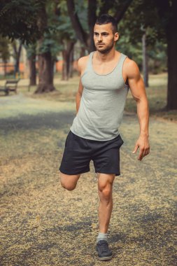 Eğitim ve egzersiz açık havada parkta yapıyor genç erkek koşucu atlet