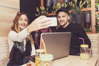 Neşeli grup arkadaş, bir adam ve kafeterya salonu, gülümseyen mutlu gülen konuşuyor ve sahip eğlenceli masada oturan iki kadın. Selfie yapım mutlu öğrenciler