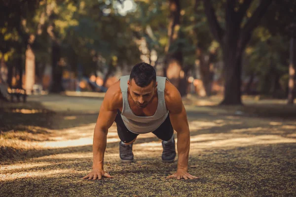 Push ups. Young muscular sportsman doing fitness exercise outdoors. Sport, fitness, workout concept
