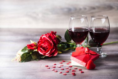 İki kadeh kırmızı şarap, Rose'u hediye ile dekorasyon ahşap masa üzerinde kırmızı kalpler tarafından. Sevgililer günü kutlama kavramı. Kopya alanı.