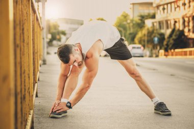 Genç sporcu gerinme egzersizi yapıyor, sabah antrenmanına hazırlanıyor. Fitness, spor, yaşam tarzı konsepti