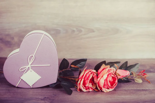 Rose and gift heart on wooden table. Valentines day celebration concept. Copy space.