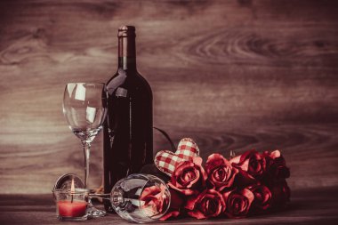 Kırmızı şişe şarap, iki bardak şarap, gül ile dekorasyon ahşap masa üzerinde kırmızı kalp tarafından. Sevgililer günü kutlama kavramı. Kopya alanı.