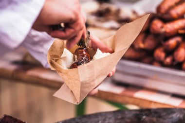 Ev yapımı sosis dolu bir kağıt torba, seçici odak ve küçük alan derinliği bir ızgara kavrulmuş holding eller yukarı kapatın