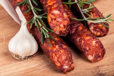 Biberiye ve sarımsak ahşap rustik arka plan üzerinde füme lezzetli sosis kapatın. Üstten görünüm.