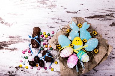 Paskalya gingerbread çerezleri, çikolata yumurta ve ahşap masa üzerinde renkli şekerler. Tavşan ve yumurta. Tebrik kartı. Yukarıdan görüntüleyin. Kopya alanı.