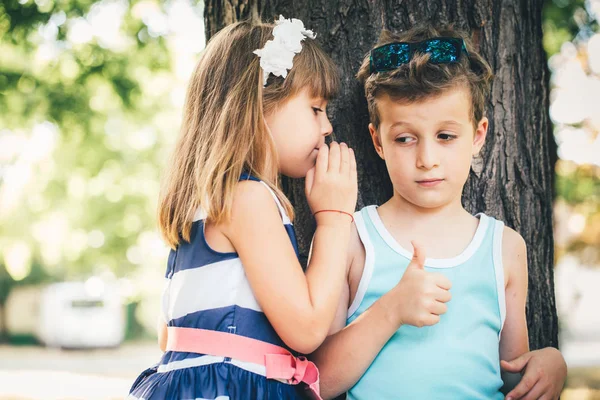 小可爱的男孩和快乐的女孩在公园里玩 玩得很开心 女孩在男孩耳边窃窃私语一个秘密 — 图库照片