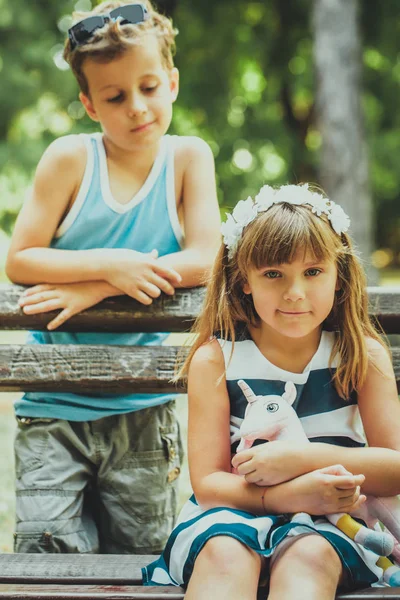 小可爱的男孩和快乐的女孩站在公园的长凳上 玩得很开心 — 图库照片