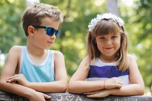 小可爱的男孩和快乐的微笑的女孩站在公园的长凳上 玩得很开心 — 图库照片