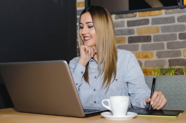 Kafede masada grafik tasarımcı oturma ve yeni bir proje üzerinde çalışıyor dijital tablet ve bilgisayar araçları kullanarak.