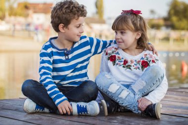 Kız ve erkek sahilde günbatımı anda oynamak. İlk aşkım. Mutlu çocuklar iyi vakit geçiriyor göl keyfi.
