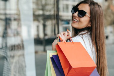 Alışveriş torbaları bol açık havada güzel genç kadın. Sürpriz ile moda giysiler içinde genç Alışverişkoliğin kadın portre yüz o gördüğünüz gibi pencere alışveriş adlı yeni bir elbise