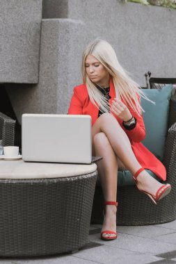 Tek mutlu kadın bir dizüstü bilgisayarda bir kafede oturup çizgi tarama