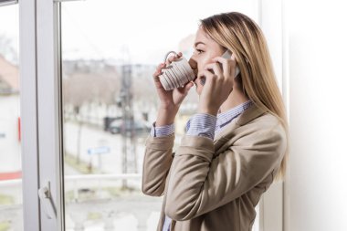 Kahve molası. Ofiste ayakta ve Evet genç gülümseyen bir işkadını. İş, eğitim, yaşam tarzı kavramı