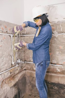 Female construction engineer planning how to install water pipes in the bathroom and keep measuring tape ruler in hand clipart