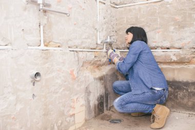 Olumlu tutum ile onun banyo lavabo boru tamir zeki kadın. bir iş aracı kullanarak. Seçici odak ve küçük alan derinliği