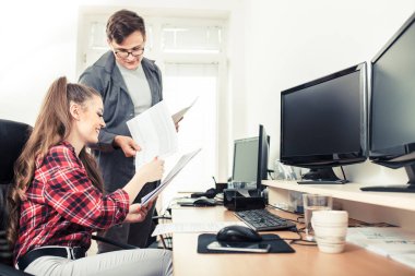 Çalışma arkadaşları gülümseyerek ve masa başında office belgelerinde paylaşımı
