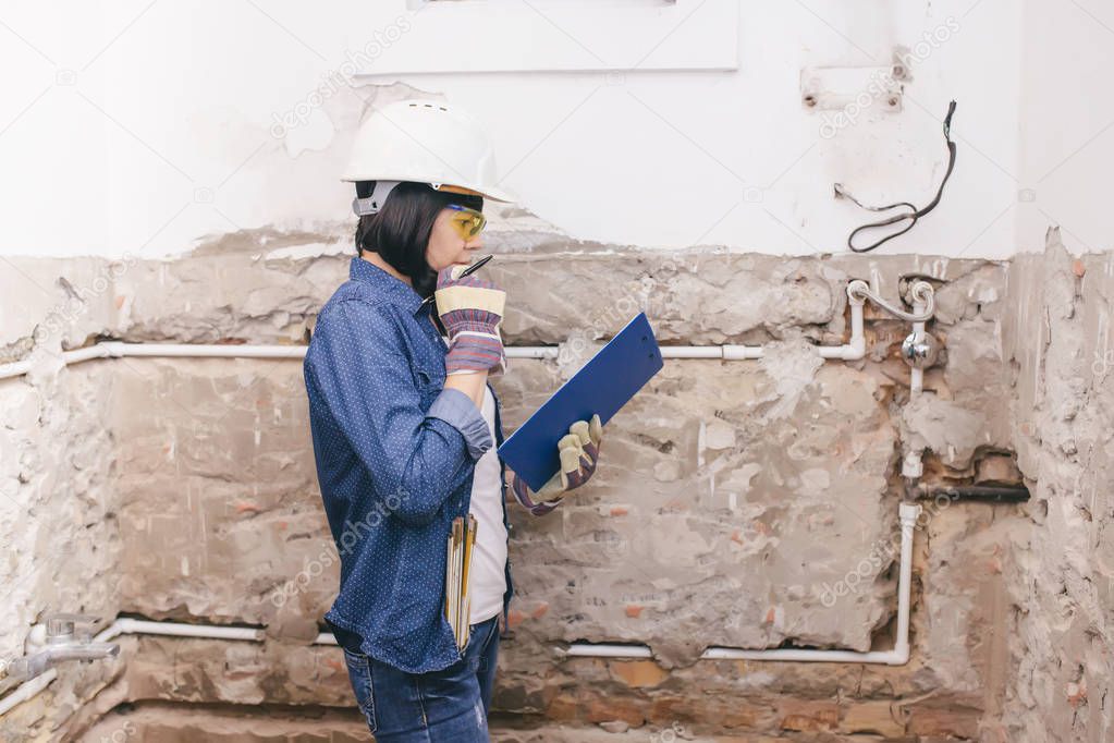 Female construction worker planning how to repairing bathroom sink pipe with  positive attitude. using a work tool. 