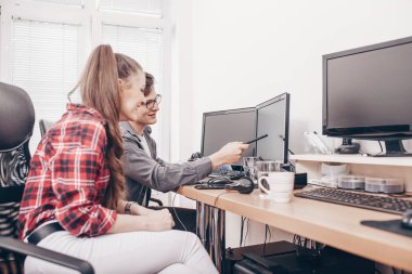 Mutlu genç meslektaşlarının masaüstü bilgisayarları kullanan ve yeni fikir tartışırken coworking ofisinde oturan görüntü.
